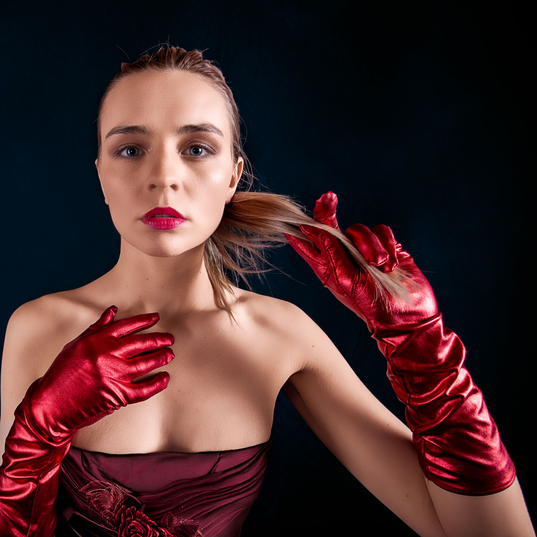 Profesjonalne zdjęcie w stylu Fashion. Odkryte ramiona, czerwone rękawiczki na dłoniach.