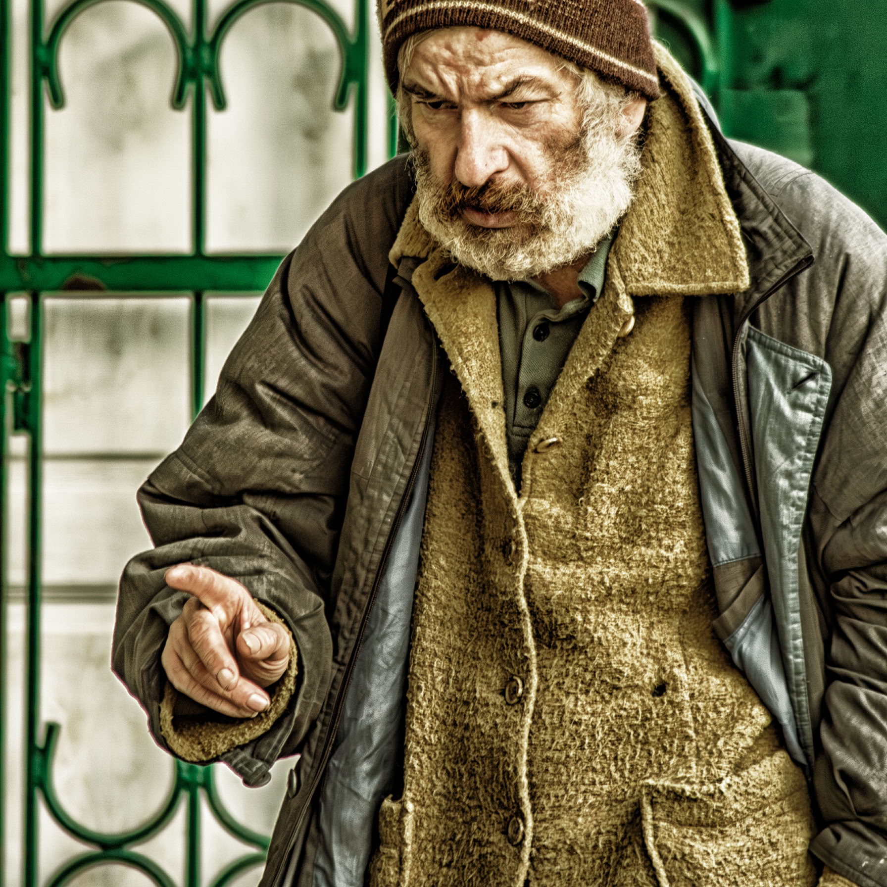 Starszy człowiek z brodą, w starym ubraniu, wskazuje palcem, jakby chciał powiedzieć "oto moja rada".