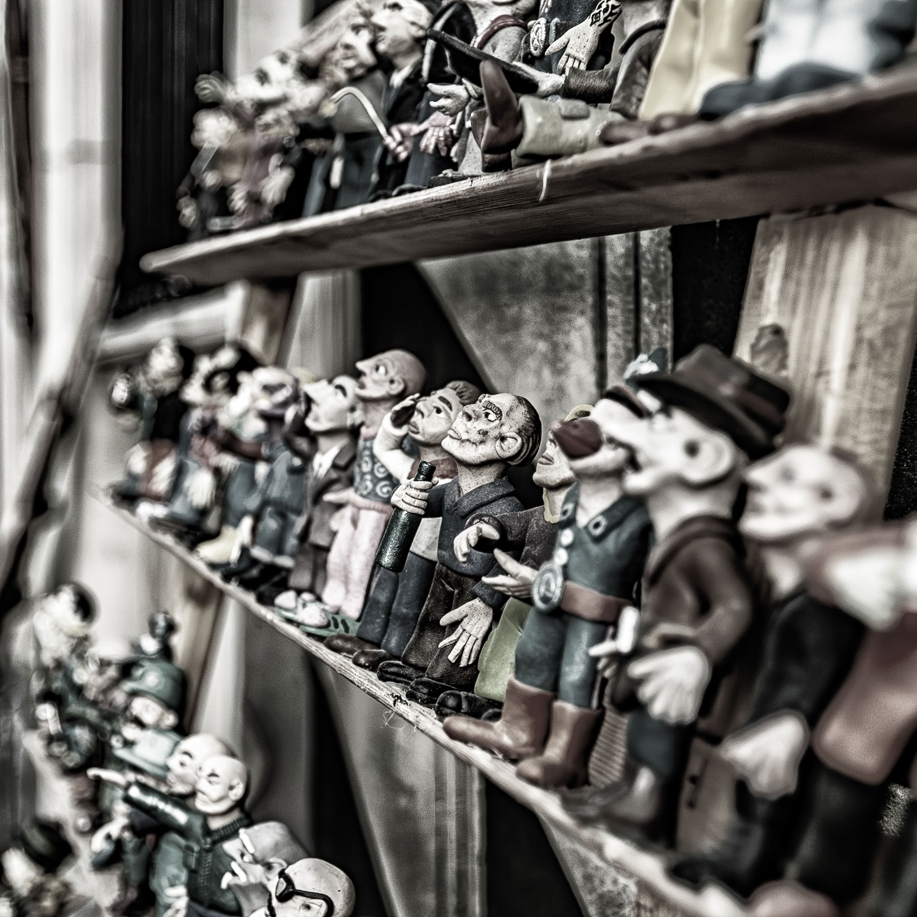 Na kilku półkach stoją drewniane lalki, ręcznie robione.